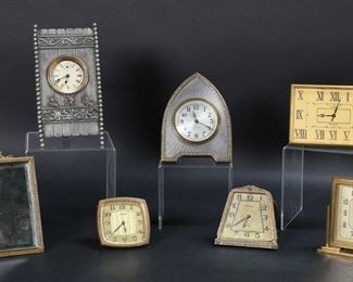 302	7 Desk & Travel Clocks	Lot of 7 desk and travel clocks. New Haven clock with mirror, Sessions art deco boudoir clock, Elgin brass 8 days circa 1932, Lux art deco table clock with 30 hour pin pallet movement, Seth Thomas Hurdle table clock with cherub motif circa 1890-1910, Doxa Watch Co., Waltham 37s 8 days with rose motif. Sessions 5 1/4"H. All untested. All with some wear and minor losses to patina on cases. Chips, scratches and desilvering to mirror on New Haven; chips to crystal on Doxa, minor losses to numerals; Waltham rose discoloration to face and losses to numerals.
