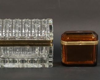 322	Lot of Glass Perfume Bottles & Dresser Boxes	6 piece lot of glass dresser items. Crystal dresser box / jewel casket, 7"L x 5 3/8"H; amber glass dresser box, monogrammed, 4 1/4"L x 4"H; amber glass perfume bottle with etched bird and flower decoration, possibly Moser, 4 7/8"H; yellow glass perfume bottle with etched floral decoration, 5 1/2"H; cranberry to clear crystal perfume, 6 1/4"H; Lalique for Nina Ricci Coeur Joie heart-shaped perfume, 6"H. Crystal dresser box brass mount for lid detached from box and chips to rim under mount; amber dresser box discoloration and oxidation to brass, Lalique bottle stopper frozen and large chip and hole to base.
