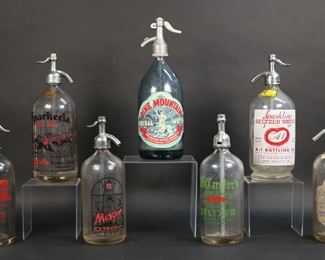 330	7 Vintage Glass Seltzer Bottles California & NY	7 vintage glass seltzer bottles / soda siphons. New York: Guy's Mac Donough Club Plattsburgh, Maccarter's J. Babad, London Beverage Co. New York City, Morgan Sparkling Carbonic Seaside Beverage Abe Feldman Rockway Beach; California: A-1 Bottling Co. Los Angeles, Pine Mountain blue glass with paper label, Sparkeeta Club Soda Sparkletts Los Angeles. Sparkeeta bottle 12"H, Pine Mountain 13 1/4"H. Losses to painted lettering and labels on London, Morgan, A-1, Sparkletts; wear and losses to metal tops on all.
