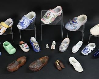 417	Grouping of Porcelain, Ceramic, and Wooden Clogs	Lot of twenty clog style decorative shoes made of a variety of materials such as porcelain, ceramic, and wood. Highlights include two miniature size Limoges pieces, a floral shoe from Royal Bayreuth, an A. Dubois shoes with a bird motif, a P.V. France piece, and two pairs of hand-carved wooden shoes. The A. Dubois ceramic shoe measures 8 1/2" in length and 3 3/4" in height. Many of the pieces are subject to crazing and in some cases hairline cracks as well as minor damage to the finish in some cases. Much of the gold decoration around the opening on the Royal Bayreuth piece has been worn away.
