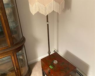 Fringed shade on floor lamp next to Japanese chest
