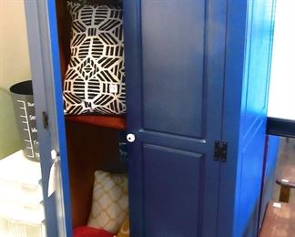 Blue cabinet full of decorative pillows.