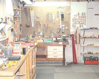 Large workroom in basement full of power tools, hand tools and painting supplies.