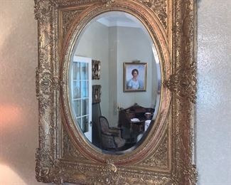 Beveled oval mirror mounted in ornate gilt wood frame