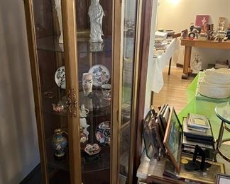 This octagonal display case with glass shelves contains several decorative items, including the two figurines.