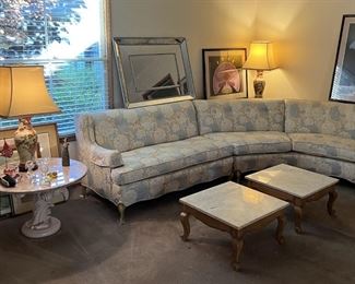 This living room scene includes the vintage sectional sofa, two rectangular tables, the round side table, a pair of lamps, an Erte print (one of two in the sale), and a wall mirror (look for its match in the other pictures).