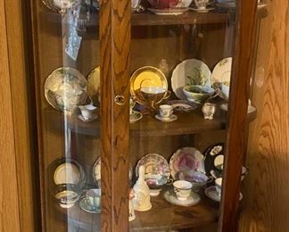 Rounded curio w cups/saucers