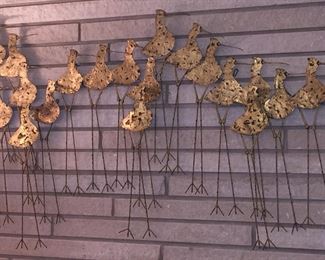 Long-legged Sandpipers crafted of metal are joined for this whimsical wall hanging. 