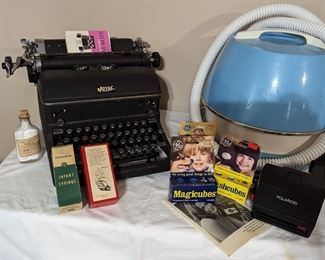 Royal typewriter, 1960s/70s collapsible hair dryer, Polaroid camera.