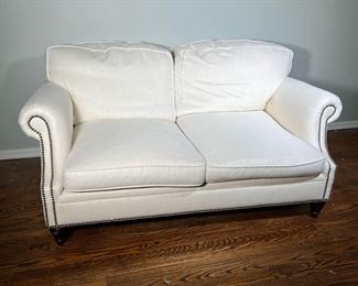 Ralph Lauren Loveseat | With white fabric upholstery, brass tacks along the bottom and scrolled arms. - l. 66 x w. 42 x h. 30 in