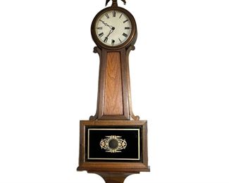 Banjo Clock | Banjo clock with a natural wood finish, eagle finial, reverse painted églomisé tablet, wood throat, dial door with glass front, Roman numeral face; includes key. - l. 32 x w. 11 in (overall)