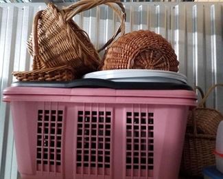 2 pink clothes baskets,  1 black clothes basket, 2 round white baskets, several natural handle baskets 