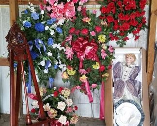 Carved mahogany easel, flower arrangments, and large doll
