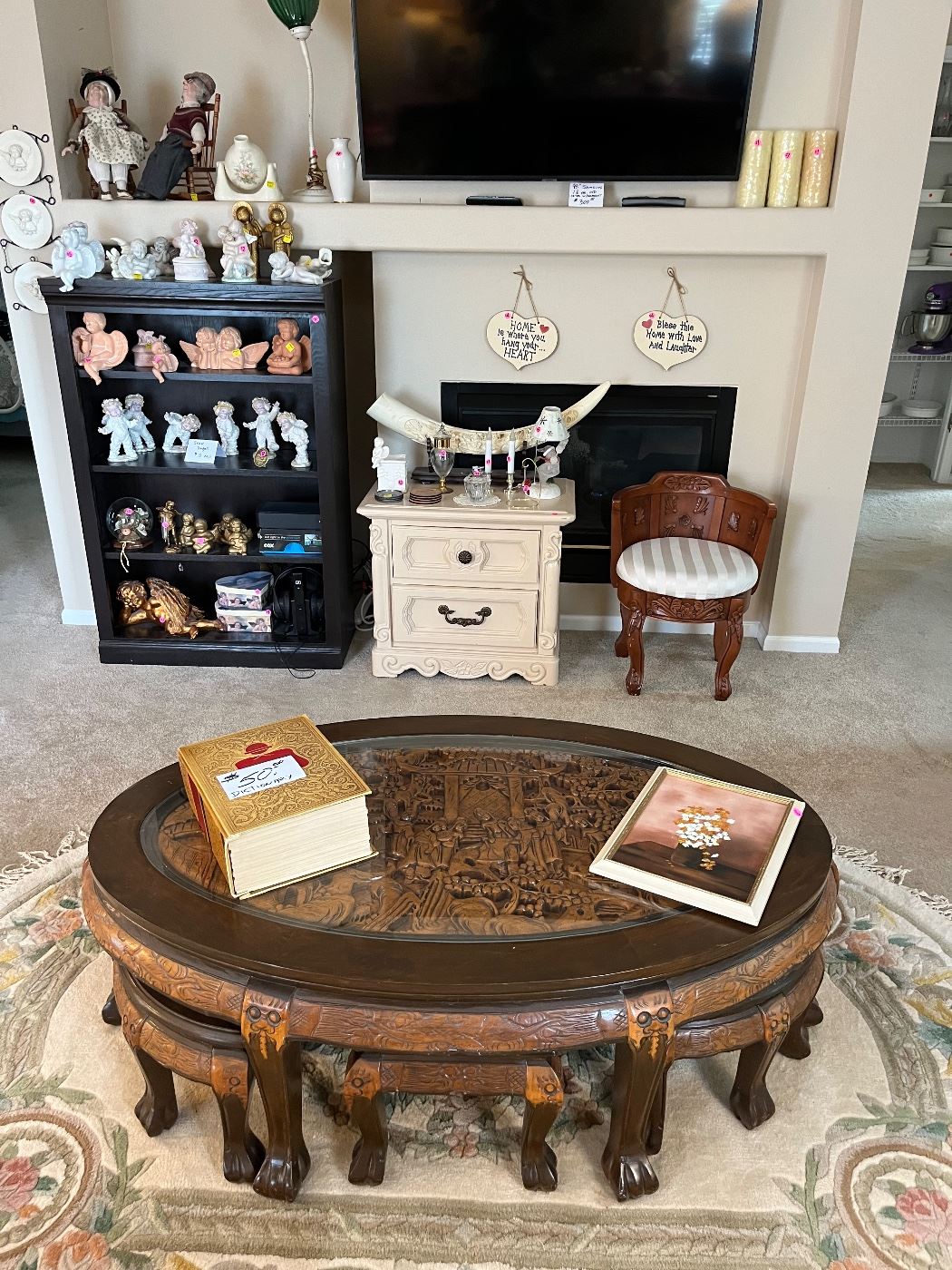 Mid-Century hand carved Asian table w/6 nesting stools. Large area rug. original oil on canvas framed art, Black bookcase loaded with collectibles. Websters dictionary. 