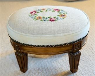 Petite oval needlepoint stool measuring 16" long, 12" deep, and 11" tall, in excellent vintage condition.