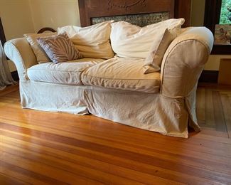 Slip-covered, two-cushion couch with two pillows.