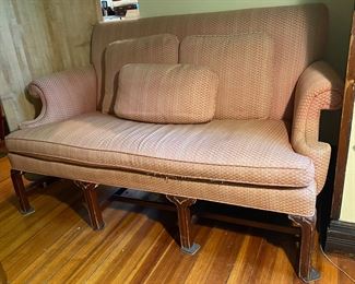 Pink upholstered, high-backed vintage Georgian-style settee with wood legs.