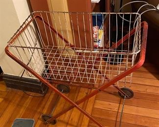 Vintage red metal laundry basket on wheeled cart.
