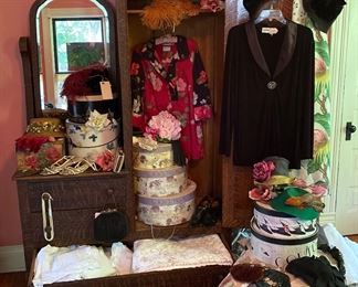 Upstairs bedroom is full of women’s clothes & shoes, vintage hats, vintage purses, hat boxes, vintage luggage & many types of vintage fabric: drapes, flour sacks, quilt remnants & scarves.