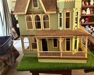 Doll house with table that has wheels. Tops come off top of house for moving. 