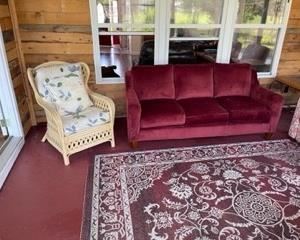 red sofa,  ratan arm chair w/ cushions, indoor / outdoor rug
