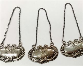 A SET OF THREE WALLACE STERLING LIQUOR BOTTLE TAGS FOR VODKA, BOURBON AND GIN.  2" WIDE.  26.2 GRAMS