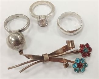 THREE MARKED STERLING SILVER RINGS AND ONE PIN: SIZE 6 3/4 RING WITH HALLOW BOBBLE.  NOTE DENT,  SIZE  5 3/4 MODERN POLISHED RING WITH CZ ,  SIZE 7 1/4 BAND RING OLDER SIGNED STERLING PIN WITH PRONG SET BLUE AND RED RHINESTONES.  2.25" TALL,  TOTAL WEIGHT 20.0 GRAMS
