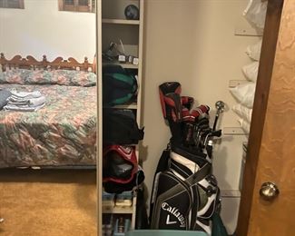 A closet full of golf items.  Clubs,  lots of golf balls, shoes and more.  Callaway clubs have been sold, but others are there (behind the mirror)