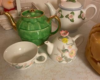 A couple tea pots along with lots of additional glassware and kitchenware