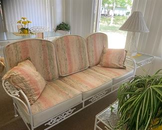 This porch holds an entire set of mid century wrought iron furniture including a three-cushion sofa, two chairs witt ottomans