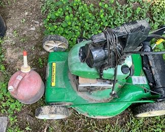 Behind the house under the canopy - lawn mower and gas can