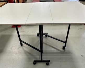 Rio Creations Folding work, sewing, dining table in White partical board on wheels for easy storage and utility.  Pretty handy item for someone who sews, folds laundry, puts together puzzles  or even an extra table when entertaining!  And it folds up!
