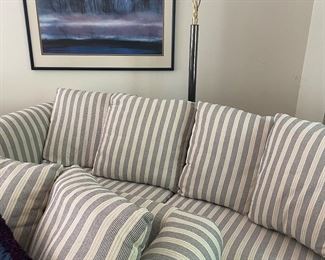 2-cushion sleeper sofa with back pillows, floor lamp and framed lithograph