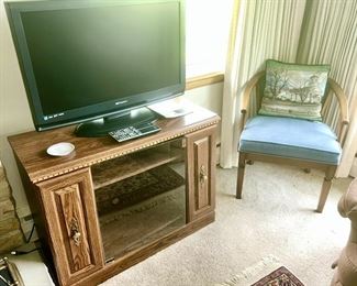Flat screen TV, TV/entertainment stand, Wooden chair with upholstered cushion