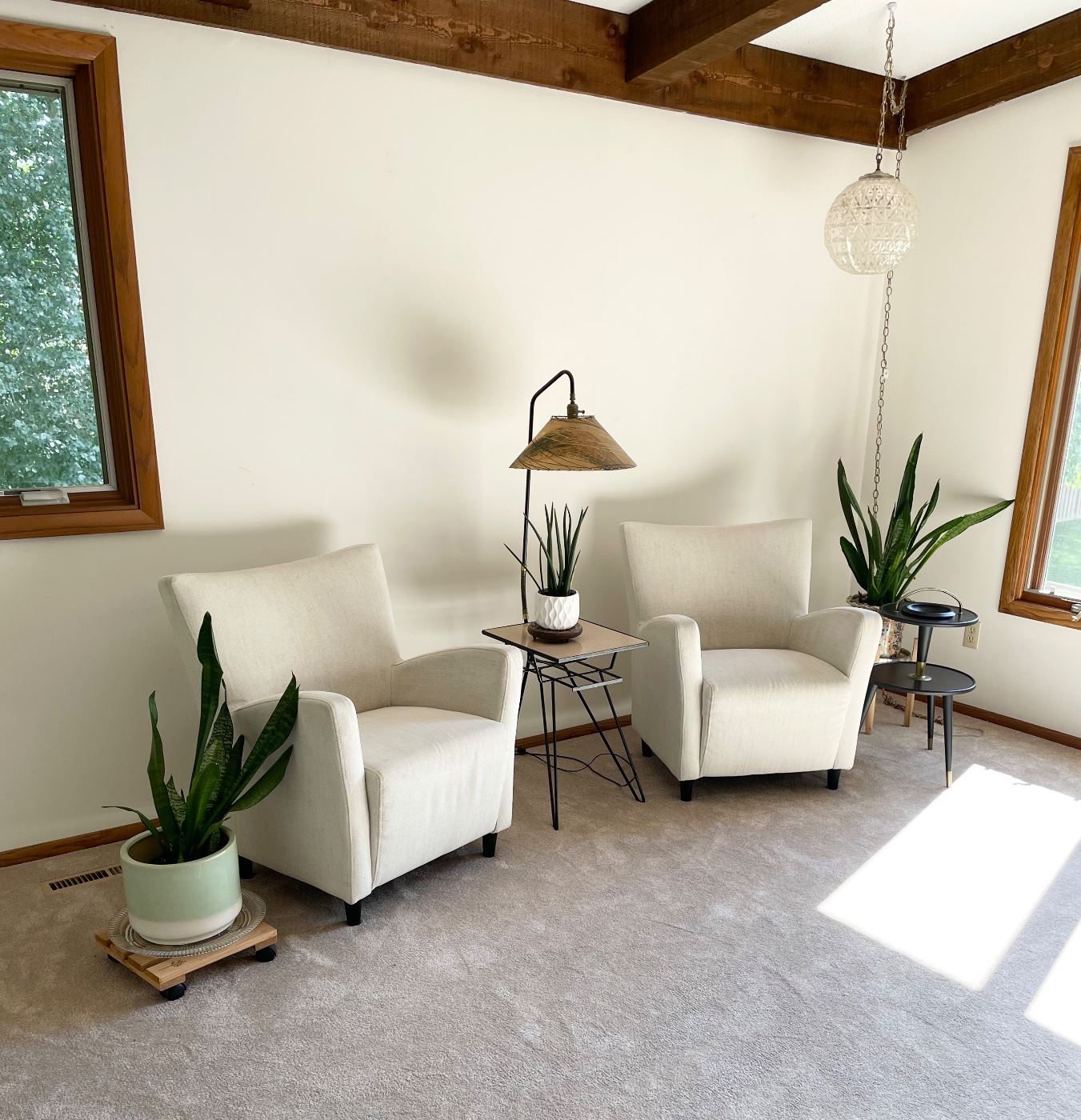 Upholstered chairs, mid century side table with lamp, houseplants 