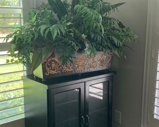 Black cabinet and large floral arrangement in tole container