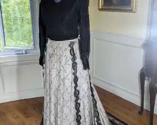 18)  ca 1900's Black and white 2 piece dress.  Bodice is in good but delicate condition except for tearing of the netting in the underarms.  There are also some pinholes in the bottom edging.  Skirt - silk with applied lace and velvet edging on  bottom of skirt.  Various  pinholes and stains.   Measures:  Bodice:  shoulder to shoulder 14",  Bust 28",  Waist 24",  Length 20".  Skirt:  waist - 30", Length - 41",  skirt length with train - 53".   $350.00