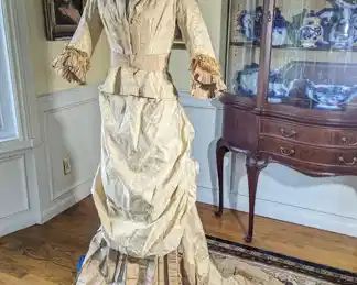 14.)  ca 1870's Reception gown, Bustle, Fish tail train.  There is some underarm damage with repair.  A tear under collar and small areas of damage on skirt bottom.  Stain on front panel. A note with the gown states it was purchased from the Met.  Condition is good.  Measurements:  Bodice:  shoulder to shoulder 12",  Bust 31",  Waist 24",  Length 20".  Skirt:  waist - 22",  Length 39".  Total length with train - 69" $575.00