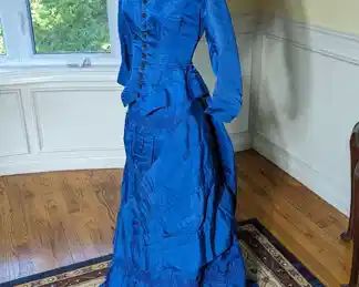 25)  ca 1880's Blue Bustle Gown.  Bodice has minor underarm discoloration and the hooks for the waist band to attach the bustle are missing.  Otherwise, in excellent condition.  Measures:  Bodice:  shoulder to shoulder 14", Bust - 26",  Waist - 22",  Length - 21".  Skirt:  Waist - 24",  Length - 40"  Total length - 61".    $ 725.00