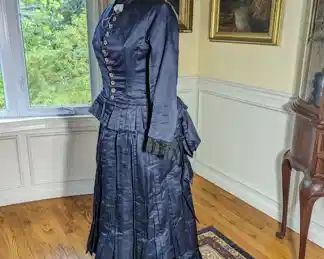 28.)  1880's Blue Bustle Gown with Mother of Pearl and Marcasite button, and Lace.  Bodice is boned and has accommodation for a bustle.  Waist band has some dry rot.  Otherwise, excellent condition.   Measures:  Bodice:  shoulder to shoulder  - 14", Bust - 28",  Waist - 28",  Length 21".     Skirt:  Waist - 28",  Length - 39",  total length - 60".       $665.00
