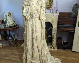35)  ca 1890's - 1900  Lace Evening/Wedding Gown - Beaded, Sequins, Faux Pearls.  Discoloration to areas of train and to bottom of the skirt.  Tears to bottom of skirt.  Underarm damage under left arm.  Beading at neck needs reattaching.  Interior silk is fragile and shattering.  Some missing beaded fringe.  Dress is dusty.  Dress displays well.   Measures:  Shoulder to shoulder - 14",  Bust - 35",  Waist - 28",  Length 65".   $450.00