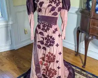 30.)  ca 1890's Pink with purple velvet and embroidered 2 piece dress.  The top sleeves have some moth damage.  There is tearing to the underarms and 1 tear on the shoulder.  There are a couple of pinholes on the back.   The skirt has 1 tear and multiple pinholes in the train.  Dress is fitting awkwardly on the form because it is to small for my form.    Measures:   Top - shoulder to shoulder 12",  Bust - 26",  Waist - 22",  Length - 15".  Skirt:  Waist  - 22",  Length - 40",  Total Length - 64".    $385.00