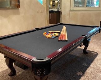 Olhausen 8' Pool Table, Mahogany Finish, Dark Grey Top, Black Fringe Pockets. Included...Balls, 4 Aminis Pool Sticks, 1 Cue Stick, Ball Rack, Table Brush. Also a 6 Panel Pad Insert and Tablecloth to Convert Pool Table into a Dining Table for Parties