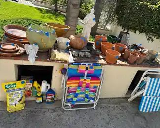 Pots, saucers, potting supplies, folding chairs, pumpkins, and St.Frances overseeing the lot