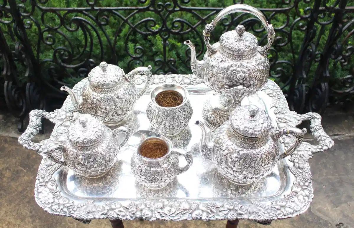 Repousse style seven piece sterling silver tea service.  W.H. is the marking on the underside.  Believe it to be by Wood & Hughes.  The tray we have chosen to show it on is silverplate.                                                                                                     NOTE:  THESE ITEMS ARE NEVER LEFT UNATTENDED OR IN THE HOUSE OVERNIGHT!