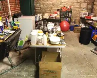Laundry room full of household items, space heaters, vacuum cleaner and cleaning supplies.