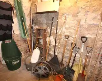 Assortment of garden tools, shovels, rakes, hoses, trimmers and more.