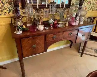 A George IV mahogany bow fronted sideboard, 19th century, with arched napery drawer, left drawer, cellaret on right, on four tapered and ring turned legs.