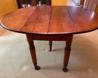 This table is soooo charming that my clients used it for their formal dinning  table with 8 antique Chippendale formal chairs.  An antique 19th century solid walnut oval drop leaf extension table with 5 legs and 4 leaves. Solid walnut five turned legs. Four solid walnut original leaves. Table is in a clean original finish. Original casters. Original custom primitive drop leaf brackets. All original parts and in good working order.  This table has a super charming primitive patch on the main table surface.