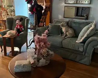 Blue couch, coat rack, hats, 